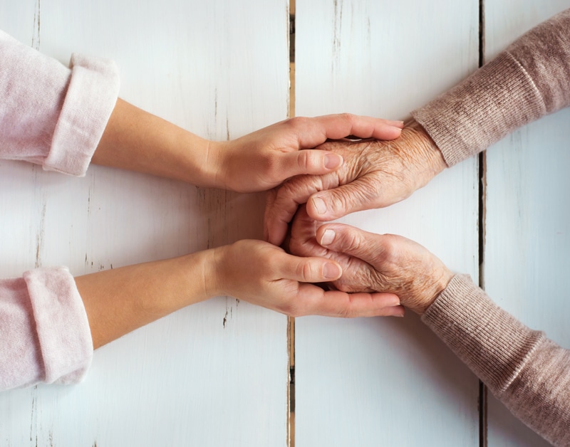 Unrecognizable grandmother and her granddaughter holding hands.