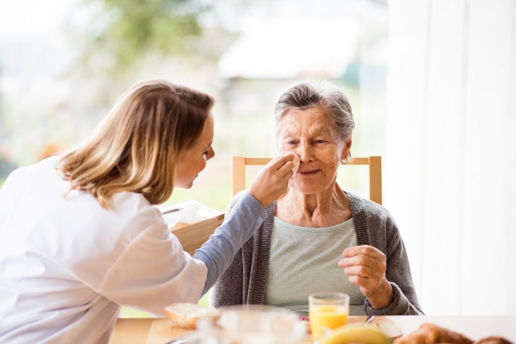 Caregiver cleaning off food on patients face