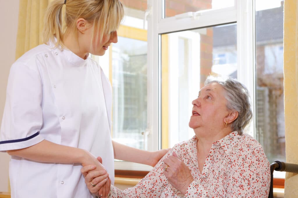 Home Caregiver holding elderly persons hand