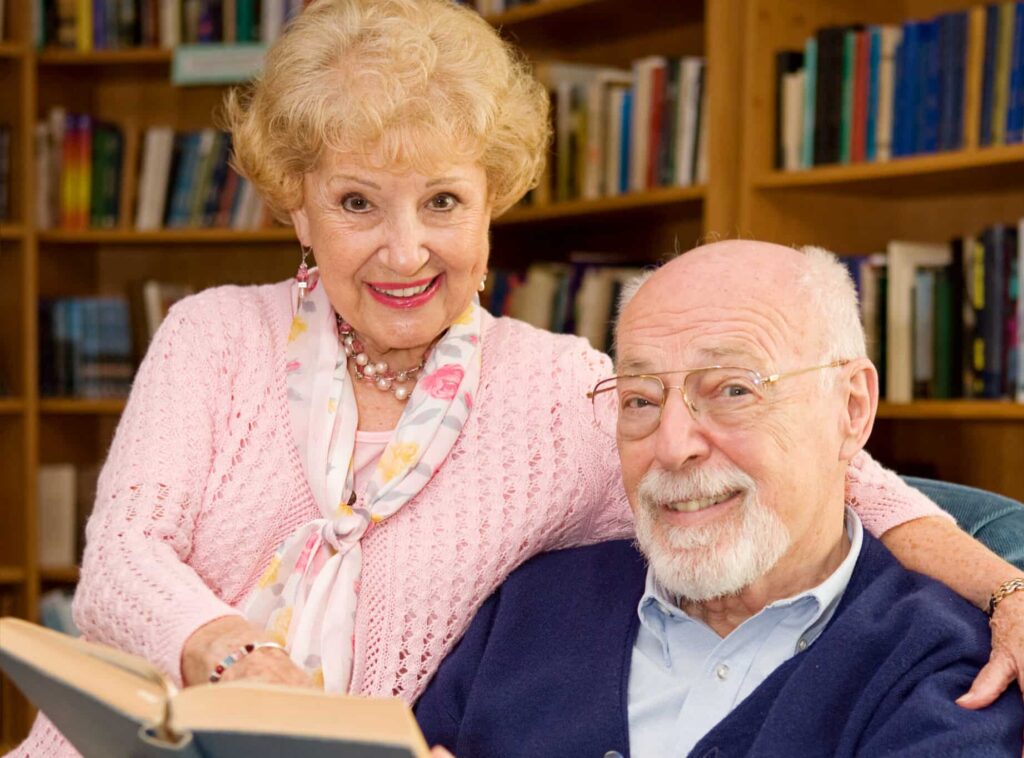 Elderly couple in a library reading a book together