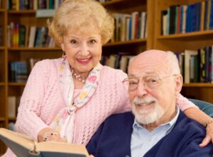 Elderly couple in a library reading a book together