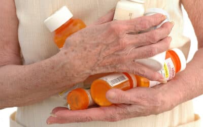 Elderly person clutching medicine bottles