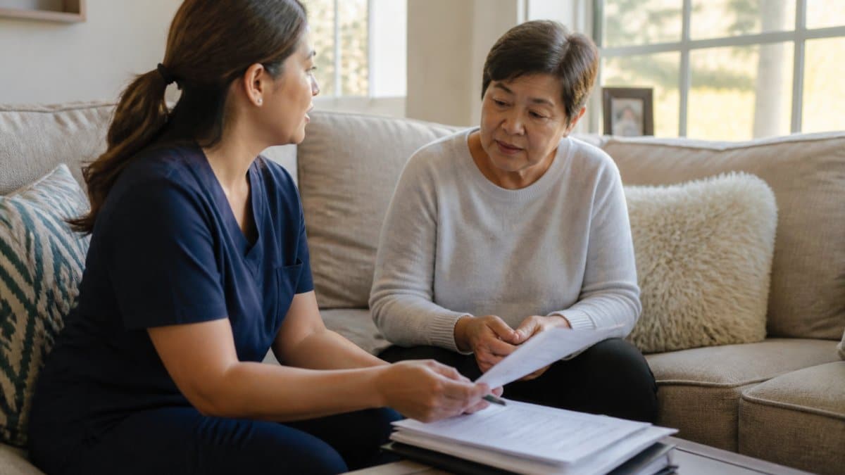 Adult child meeting with home care representative in comfortable living room, reviewing paperwork and discussing care options, natural afternoon lighting through windows